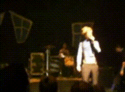 a woman singing into a microphone on a stage in a dark room