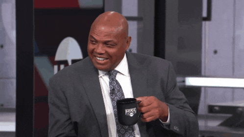 a man in a suit and tie is holding a cup that says nba