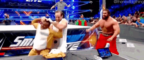 two men are wrestling in a wrestling ring with a referee in the background