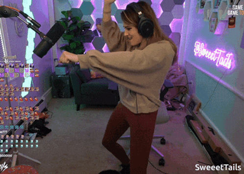 a woman dancing in front of a neon sign that says sweet tails