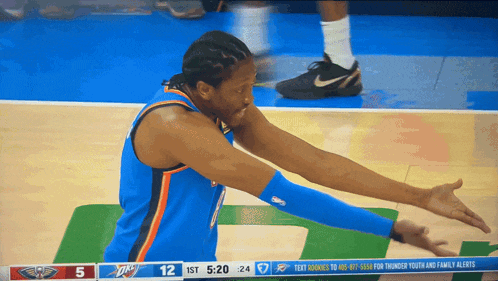 a basketball player with his arms outstretched in front of a scoreboard that says 12