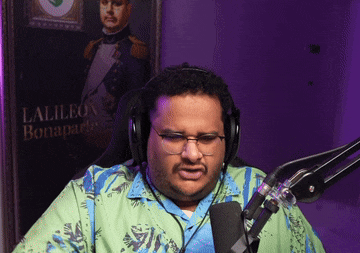 a man wearing headphones and glasses stands in front of a microphone in front of a painting of lalileon bonaparto