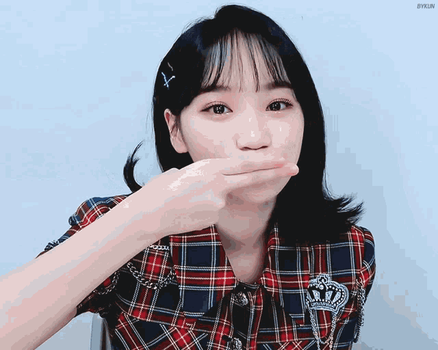a girl wearing a plaid shirt with a crown on it blowing a kiss