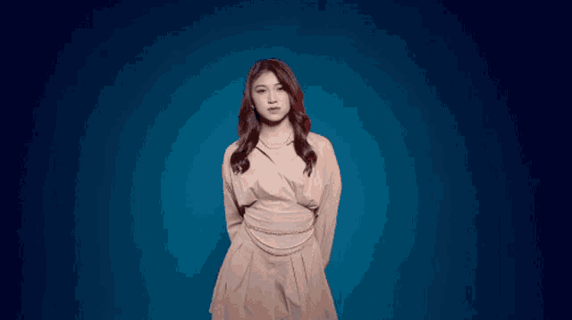 a young woman in a white dress is standing in front of a blue background .