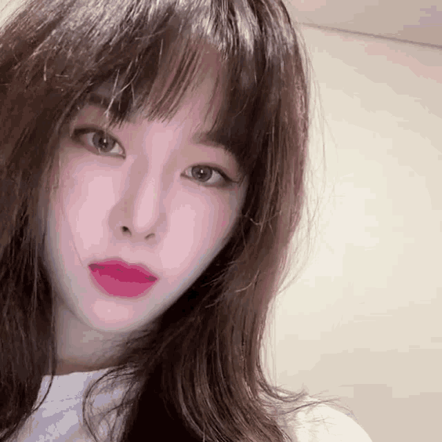 a close up of a woman 's face with long hair and a white shirt