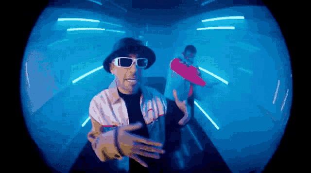 a man wearing sunglasses and a hat is standing in a blue room