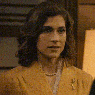 a woman wearing a yellow jacket and a pearl necklace .