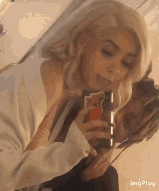 a man and a woman are taking a picture of themselves with their cell phones .
