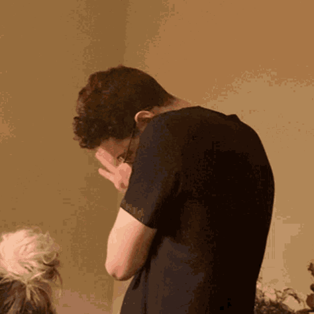 a man covering his face with his hands in a dark room