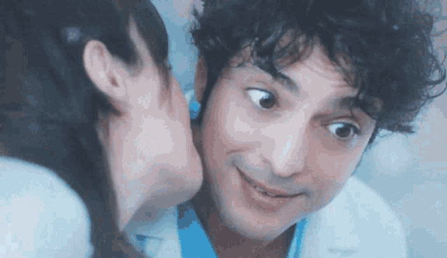 a woman is kissing a man on the cheek in a close up