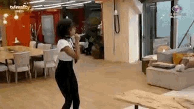 a woman is dancing in a living room with tables and chairs .
