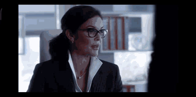 a woman wearing glasses and a suit is talking to another woman .