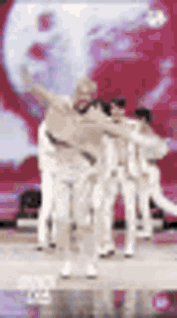 a blurry picture of a group of people dancing on a stage in front of a red background .