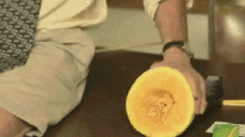 a man is cutting a pumpkin in half on a table .