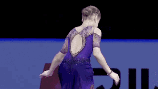 a female figure skater in a purple dress is dancing on a ice rink .
