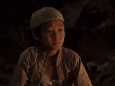 a boy wearing a white hat looks down at something