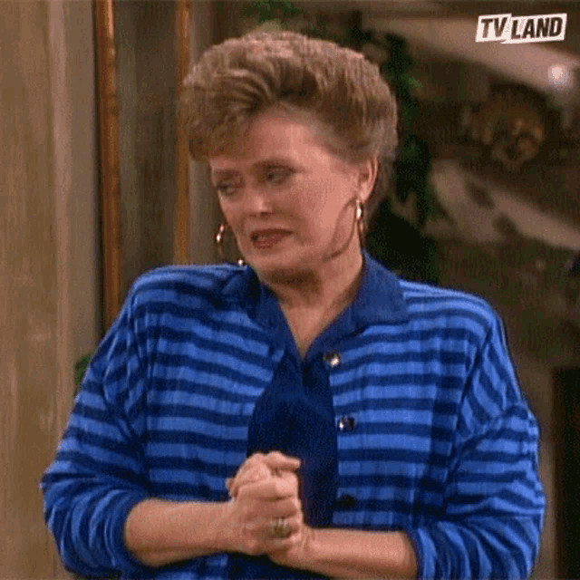 a woman wearing a blue striped sweater and a blue tie is making a funny face .