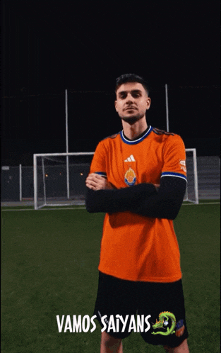 a man wearing an orange shirt with the words vamos saiyans on it