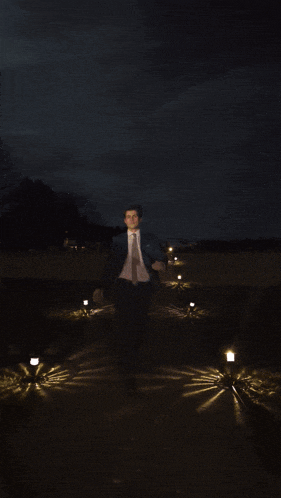 a man in a blue suit and tie stands in front of a dark sky