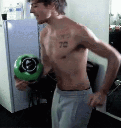 a shirtless man with the number 78 tattoo on his chest holds a green soccer ball