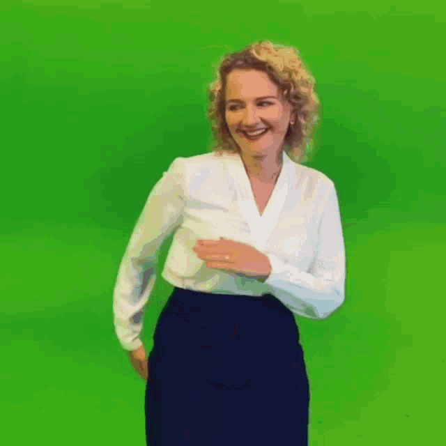 a woman in a white shirt and a black skirt is dancing on a green screen .