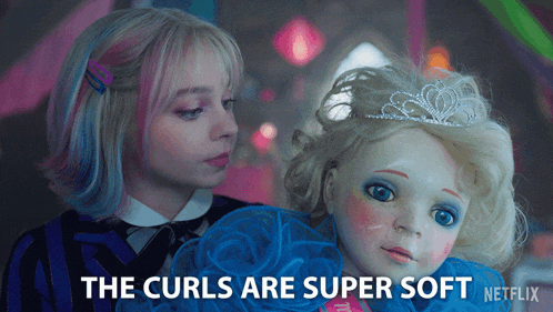 a girl holding a doll with the words " the curls are super soft "