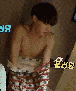 a shirtless man is taking off his shorts in a room with chinese writing on the wall .