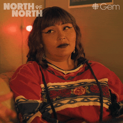 a woman is sitting on a couch in front of a sign that says " north of north "