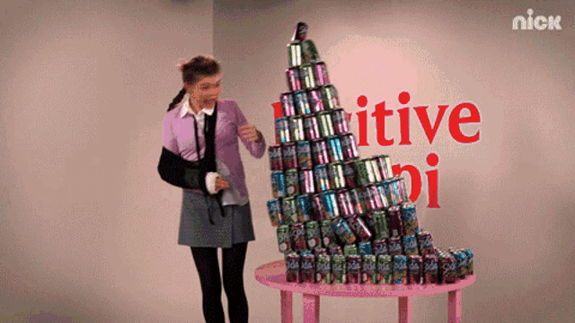 a girl is standing in front of a stack of soda cans and a sign that says " nick "