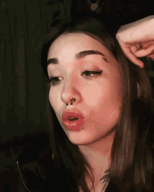 a woman with a nose ring is making a face with her mouth open