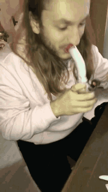 a man with long hair and a beard is smoking a cigarette