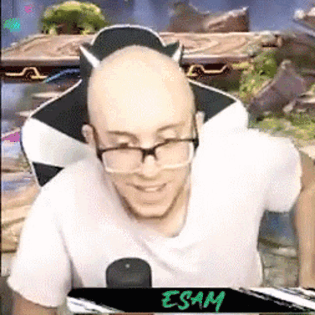 a bald man wearing glasses is sitting in front of a microphone .
