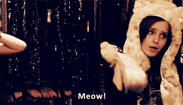 a woman in a furry hat says meow in a dark room
