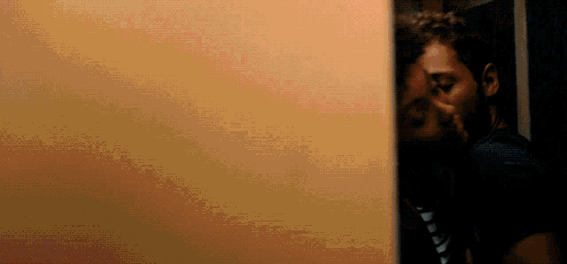 a man kissing another man behind a door