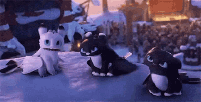 three dragons from how to train your dragon are sitting next to each other on a snowy hill .