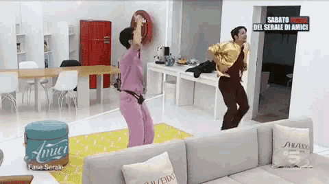 a man and a woman are dancing in a living room in front of a sign that says sagato rosse del serale di amici