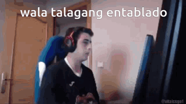 a man wearing headphones is sitting in front of a computer with the words wala talagang entablado above him .