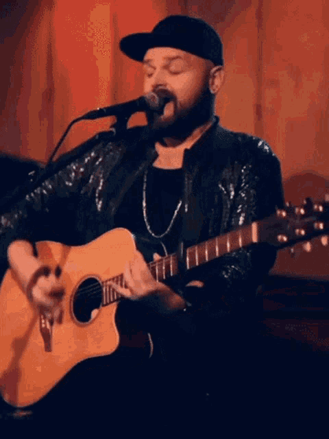 a man is singing into a microphone while playing a guitar