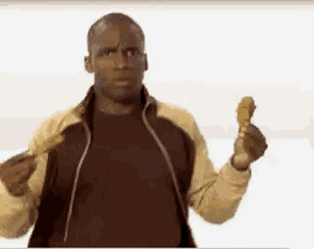 a man in a brown jacket is holding a piece of fried chicken .