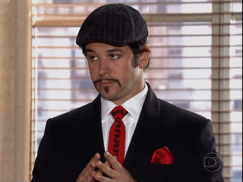 a man with a mustache wearing a black suit and red tie