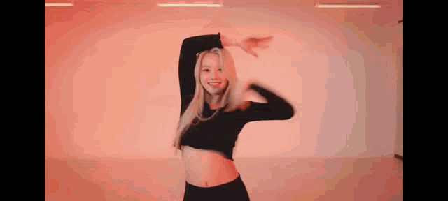 a woman in a black crop top and black pants is dancing in a dance studio .
