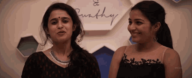 two women are standing next to each other in front of a sign that says " purthy "