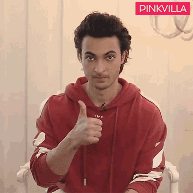 a man in a red off white hoodie gives a thumbs up sign