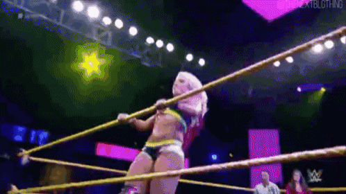 a woman is wrestling in a wrestling ring with a rope around her waist .