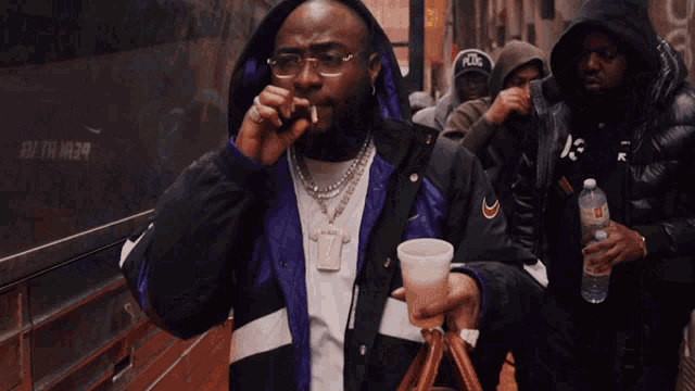 a man in a nike jacket holds a cup
