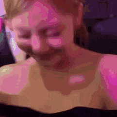 a close up of a woman 's face with pink lighting behind her