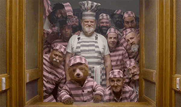 a man in a chef 's hat is surrounded by a group of prisoners