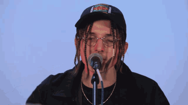 a man singing into a microphone with a hat that says gucci