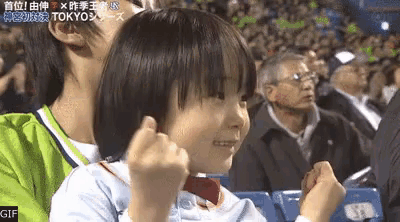 a little girl is sitting next to a man in a stadium giving a thumbs up .