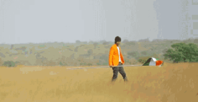 a man in an orange jacket is holding an indian flag